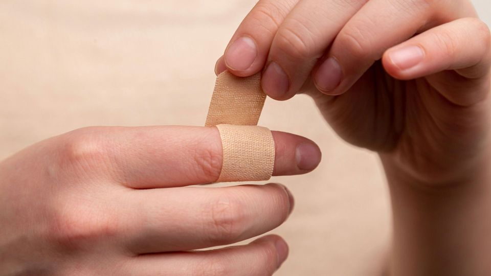 A person wraps a band aid around their finger.
