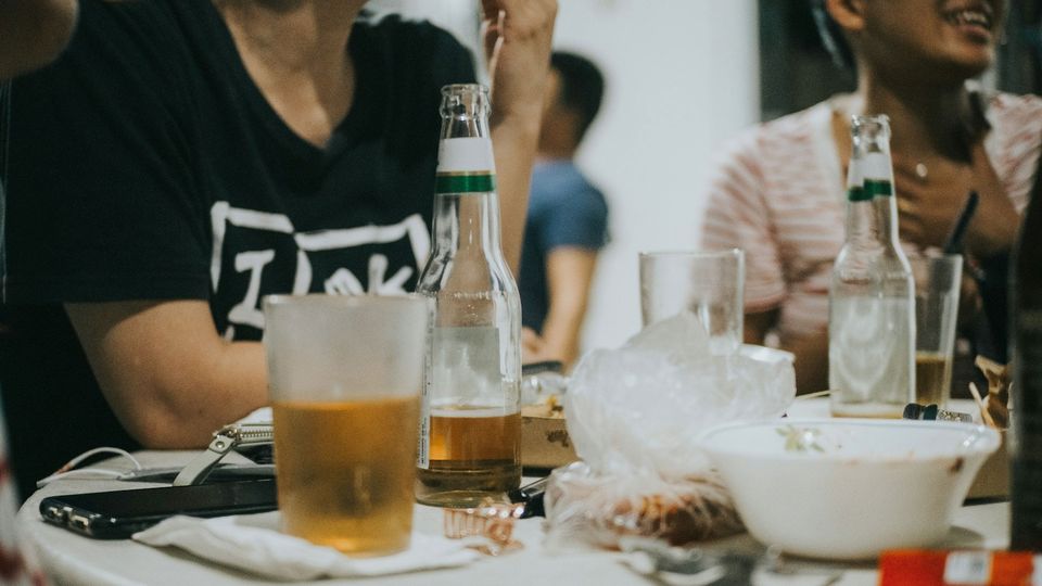 A group at a table, with beers and food bowls across it.