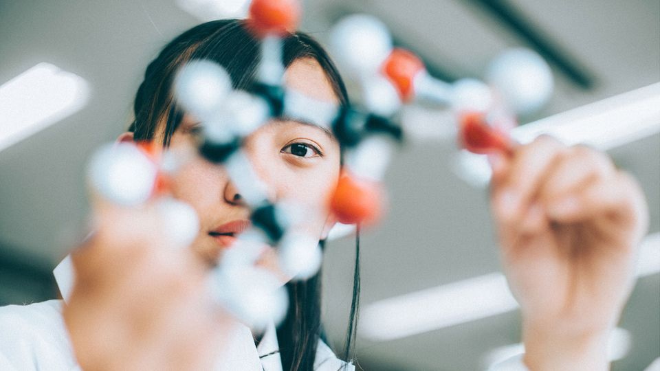 A researcher holds up a chemical structure of a molecule.