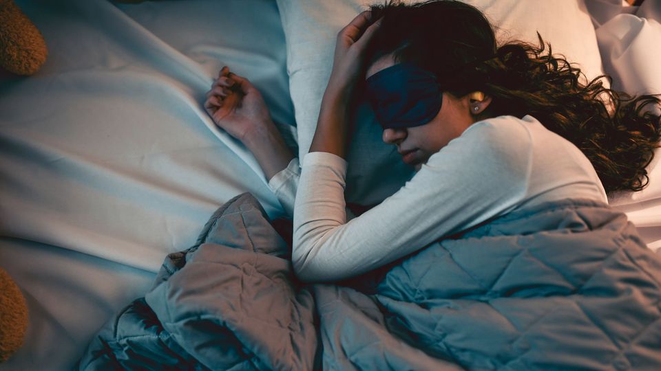 A woman trying to sleep, while wearing a sleep mask.
