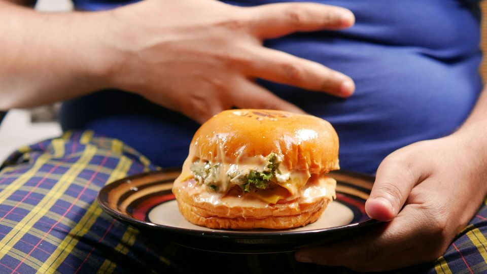 An overweight person with a sandwich.