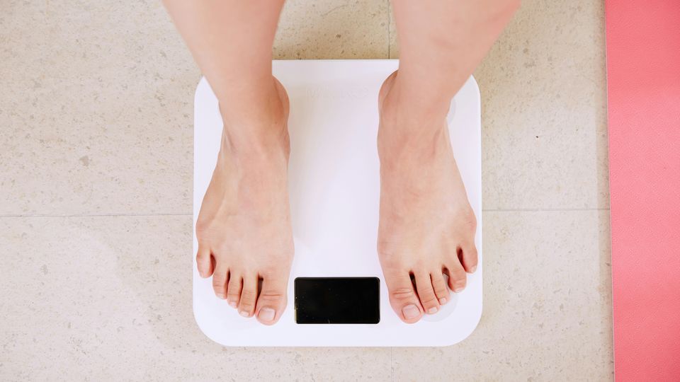 A person measuring their weight on a set of scales.