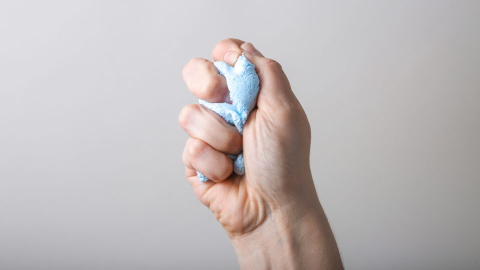 A person squeezes a plastic stress ball in their fist.