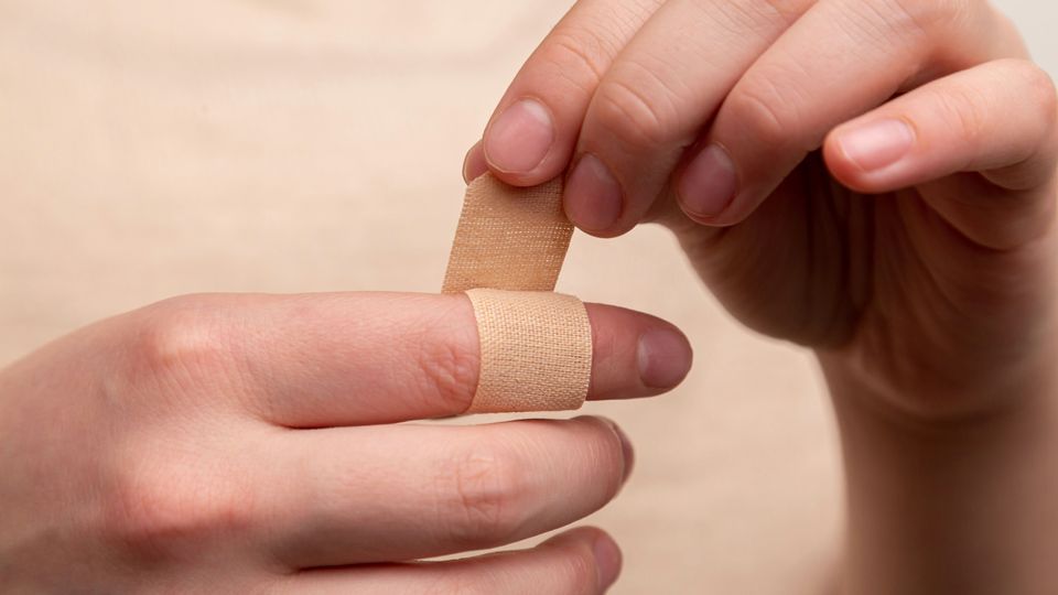A person wraps a band-aid around their finger, like how hydrogel super skin could be used to aid with wound healing.
