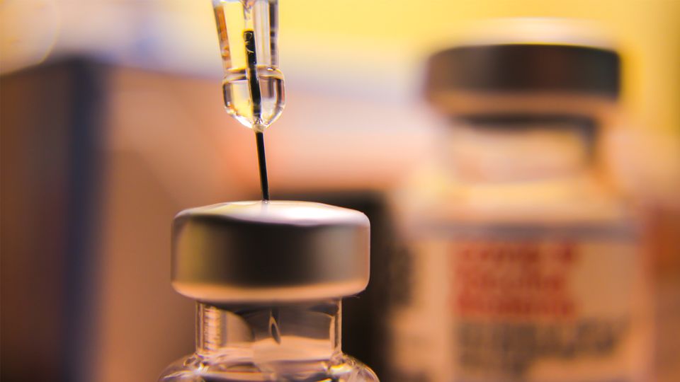A needle drawing liquid from a vaccine vial.