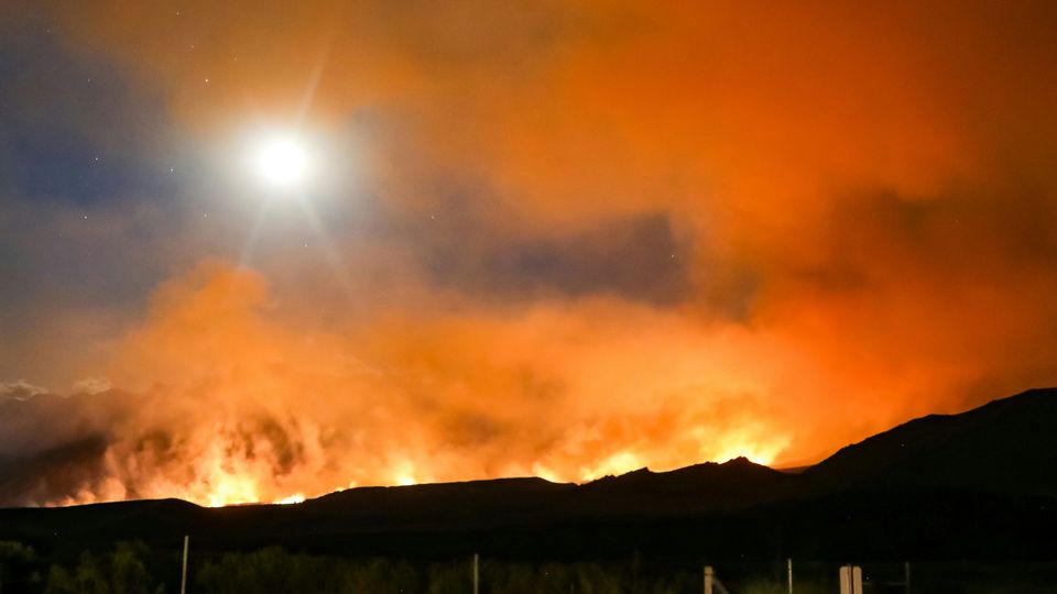 Photograph of wildfire with glowing orange smoke.
