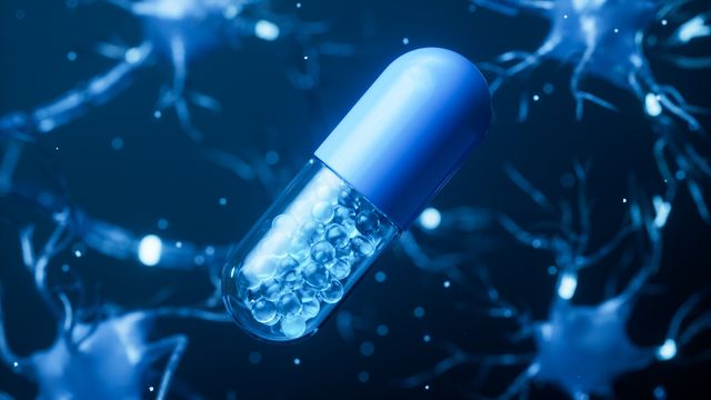 Blue and transparent capsule pill filled with small beads floating against a background of neurons, symbolizing clinical trials in neuroscience.