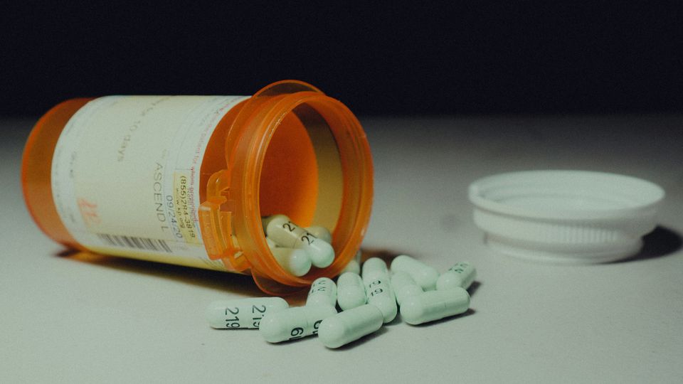 A pill bottle on its side with antidepressants spilling out.