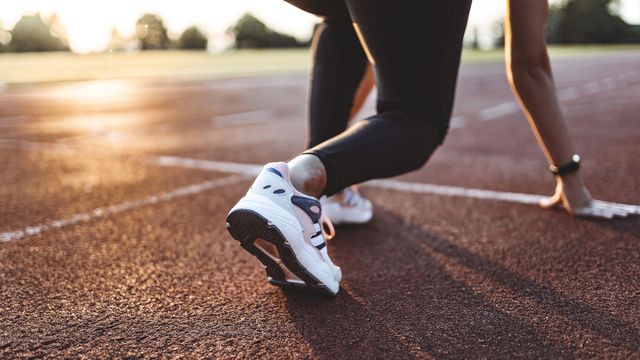 Individual on a running track in the "start" position, ready to run. 