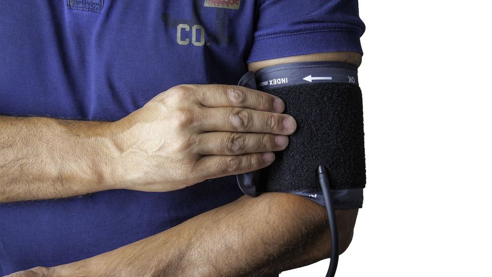 Individual wearing a blood pressure cuff on their arm.