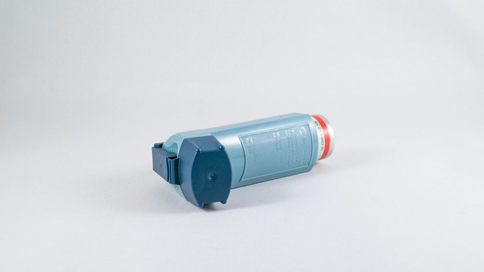 Blue asthma inhaler lying on its side.
