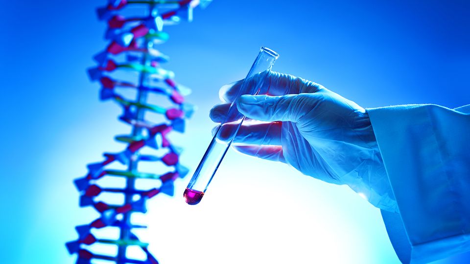 A scientist holding up a test tube with a model of a DNA double helix in the background, representing gene therapy.