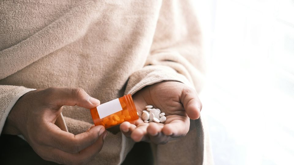 A close up of a persons hand holding some antibiotics.