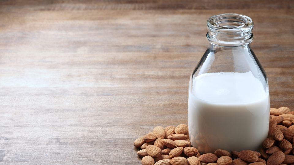 A bottle of milk surrounded by almonds.