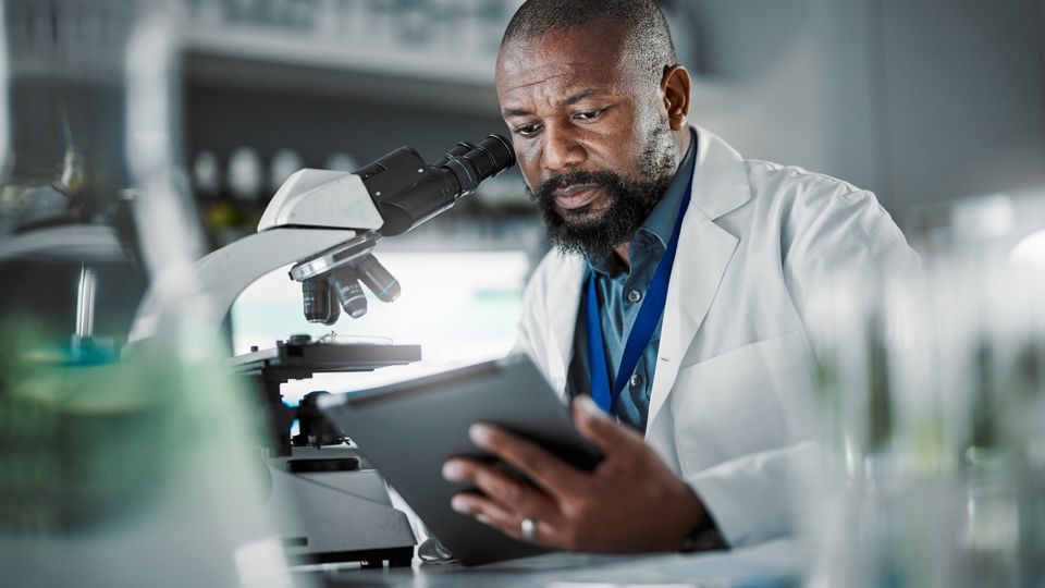 A scientist looking down a microscope.