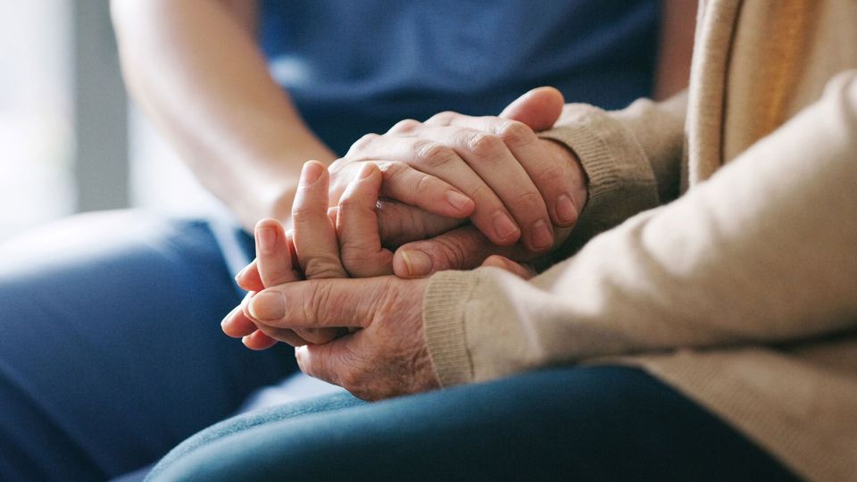 Younger and older person holding hands.