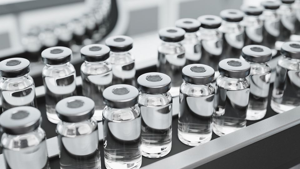 Clear vials of medicine on a conveyor belt