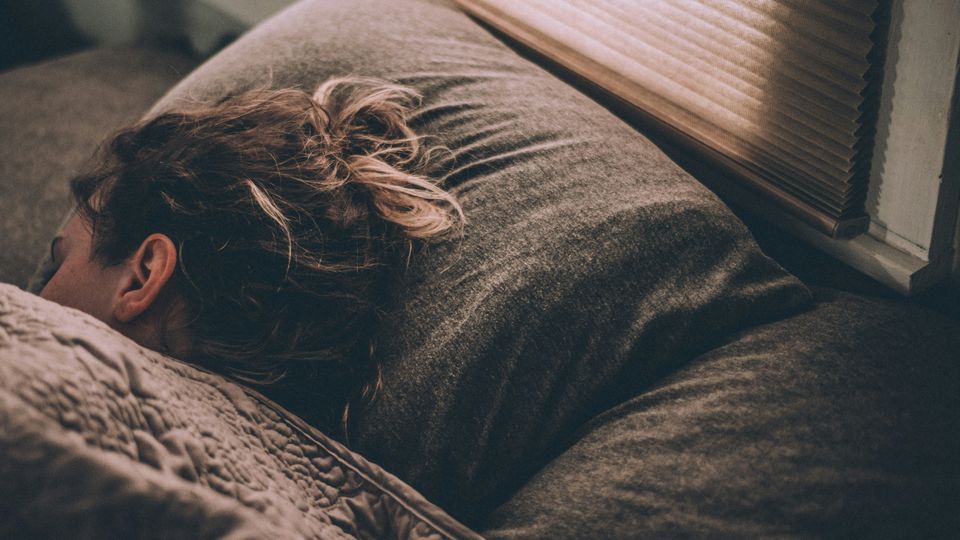 A woman sleeping in bed, facing away from the camera.
