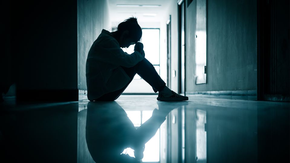 A woman sat alone in a dark corridor suffering from depression.