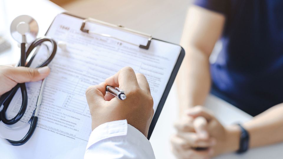 Doctor completing a form with a patient.