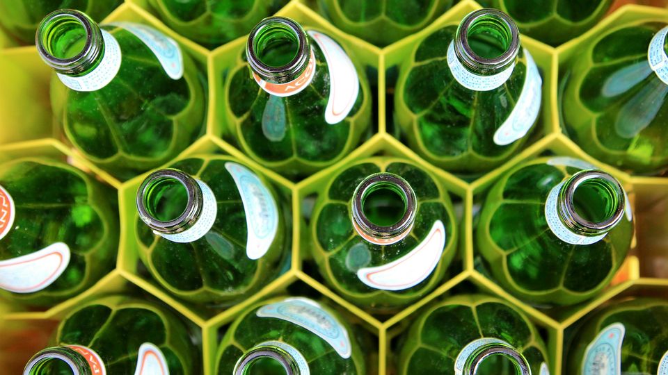An overhead photo of green glass bottles in a yellow plastic crate.