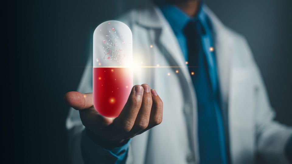 A scientist holding up a hologram of a drug molecule in a pill, representing AI-driven drug discovery.