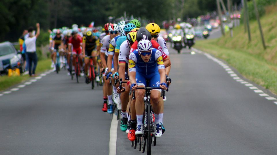 A large group of cyclists move quickly along a road.
