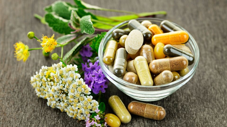 A selection of different drugs next to a variety of herbs, representing traditional natural medicines.