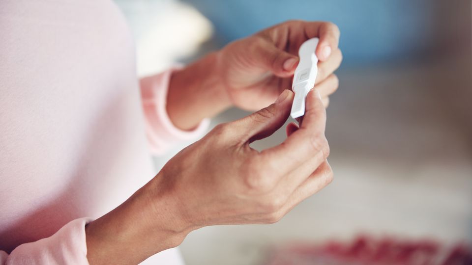 A person holding a pregnancy test.