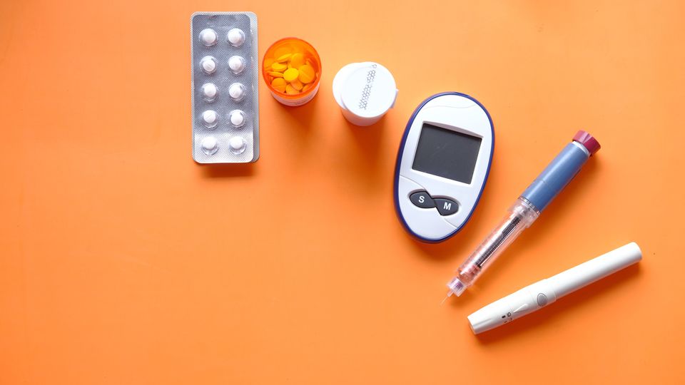 Diabetes management tools including glucose meter, insulin pen, and medication on orange background.