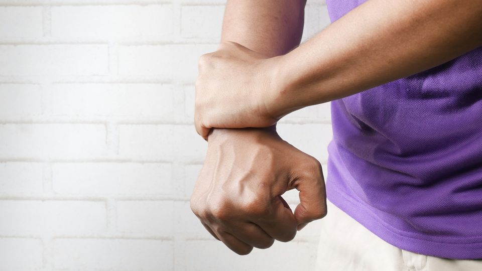Person clutching their wrist, showing discomfort associated with chronic pain.