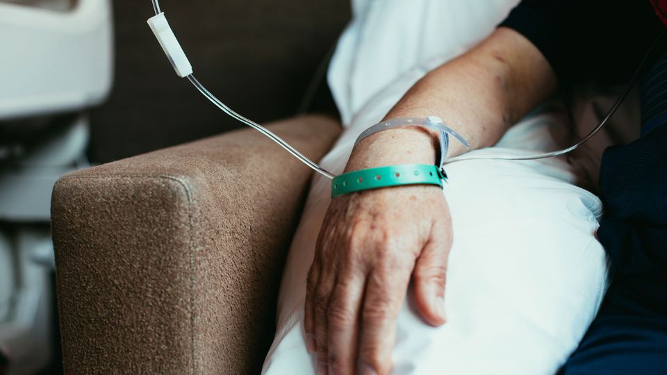 Individual receiving cancer therapy via intravenous infusion.
