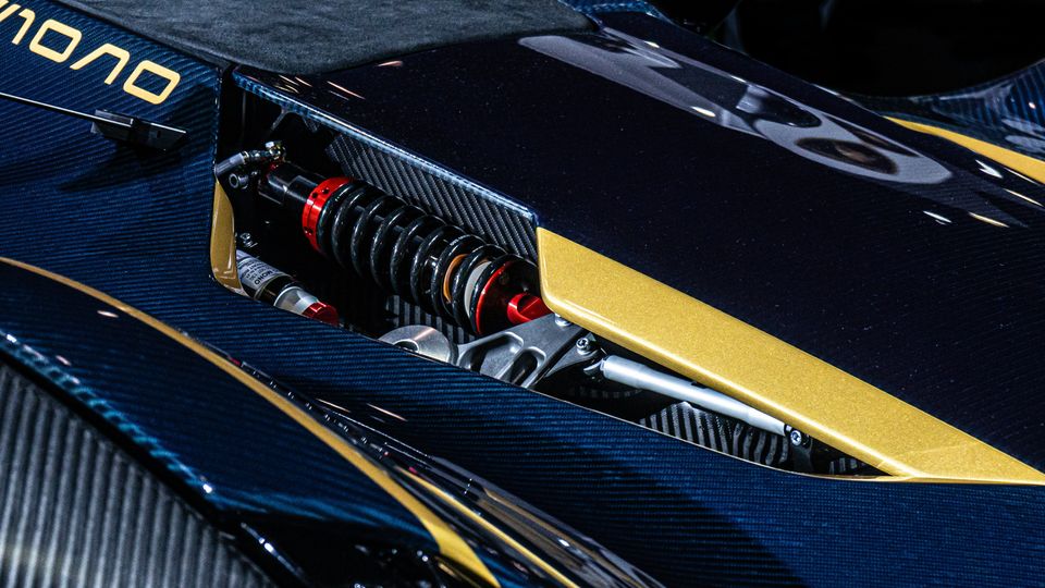 A close-up of a part of a motorcycle, made from carbon fibre and wrapped with various blue and yellow team stickers.