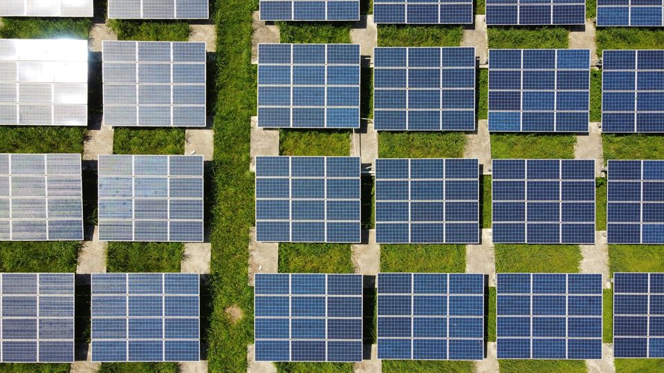 An overhead view of an array of solar panels out in a field.