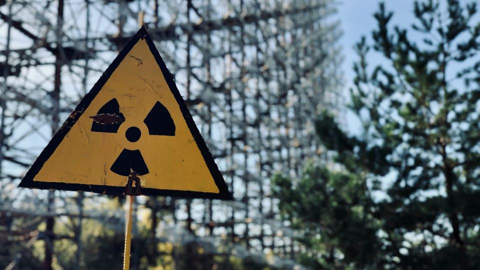 A radiation warning sign in front of a metal fence.