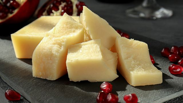 Blocks of yellow cheese on a slate slab, pomegranate seeds visible.