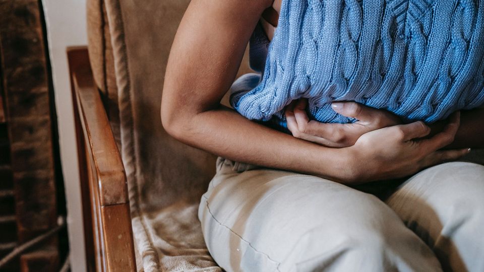 A person holds their stomach, illustrating stomach pain caused by inflammatory bowel disease.