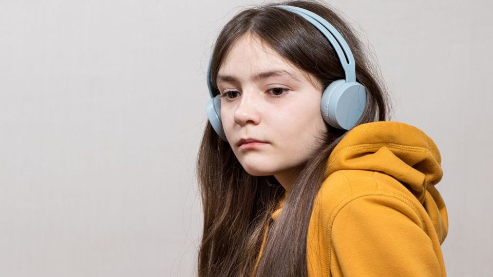 Teen girl with headphones and neutral expression, representing sensory processing in autism.