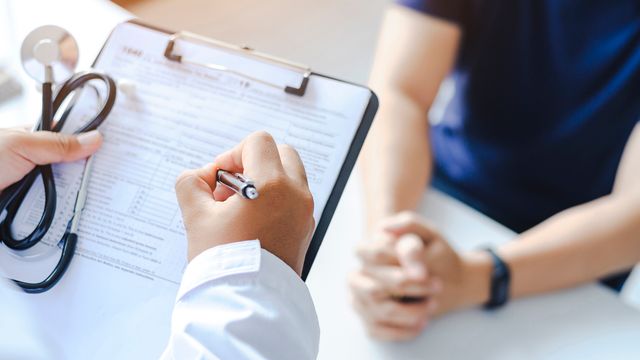 Doctor writing on a clipboard during a consultation, representing the role of biosensors in medical diagnostics. 