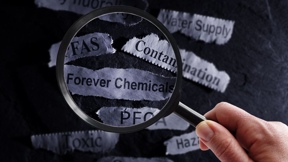 Magnifying glass focusing on words related to "forever chemicals," highlighting PFAS and contamination concerns.