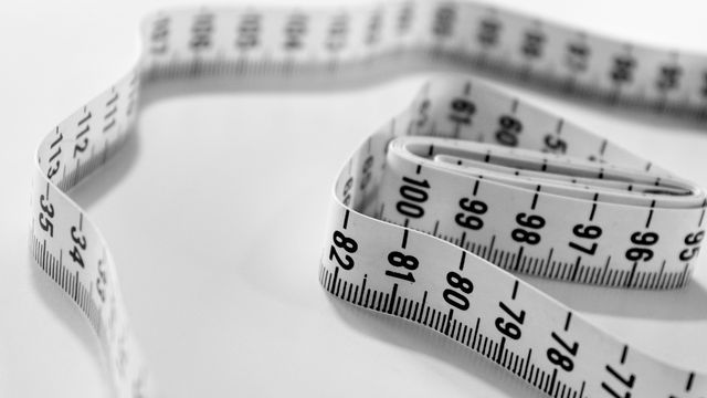 A close up of a white measuring tape used for measuring weight loss.