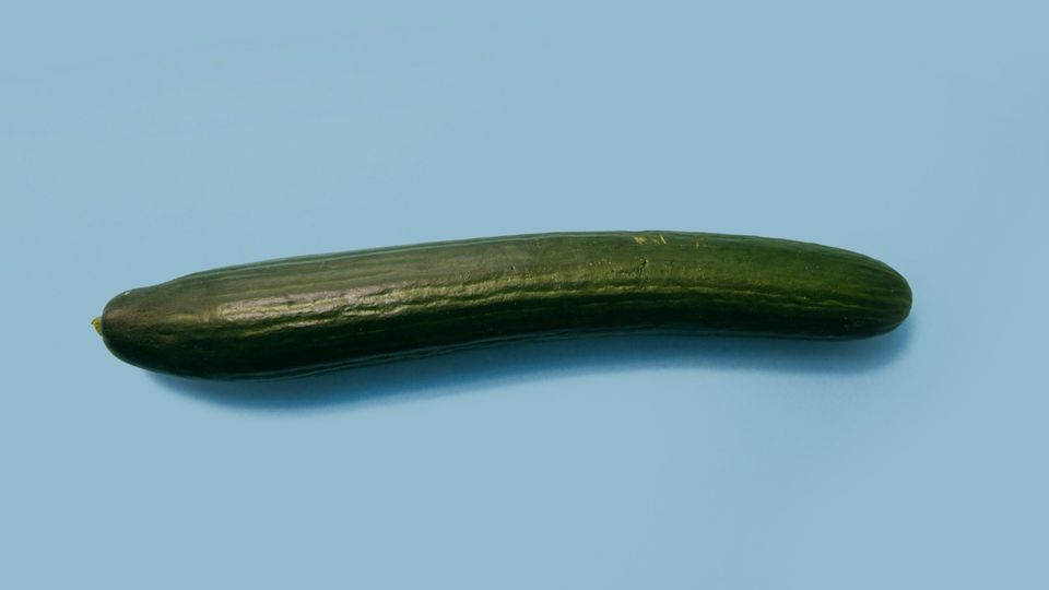 Whole fresh cucumber on a blue background.