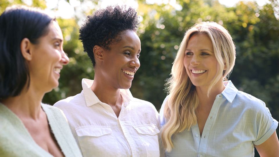 Women standing side-by-side laughing with each other.
