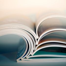 Stack of open academic journals showing glossy pages, representing scholarly publishing. 