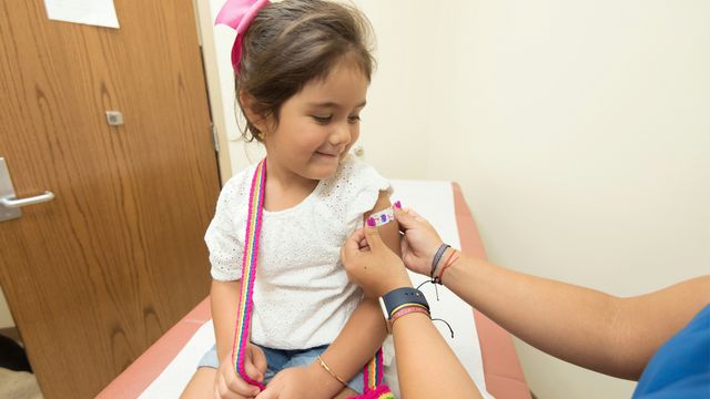 A doctor placing a plaster on the arm of a child who has just received a vaccination.