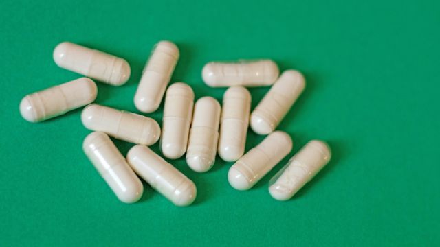 A group of white pills containing penicillin against a green background.
