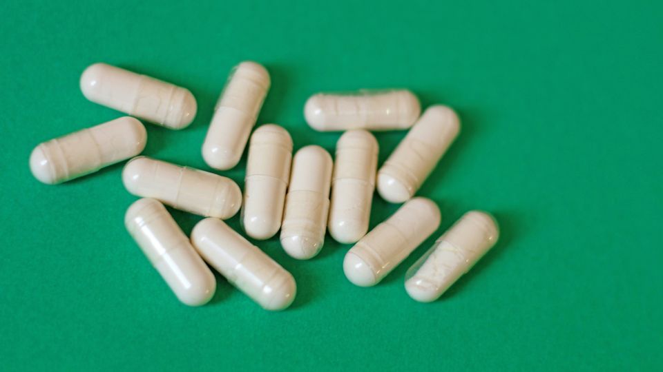 A group of white pills containing penicillin against a green background.