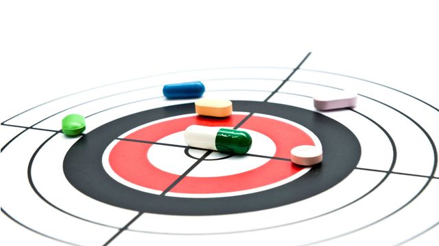 Various drug pills on a target, representing precision medicine. 