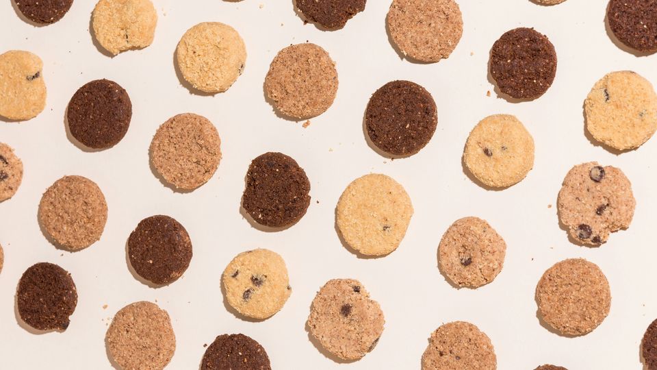 A series of biscuits/cookies, some pale, some brown, on a white background.
