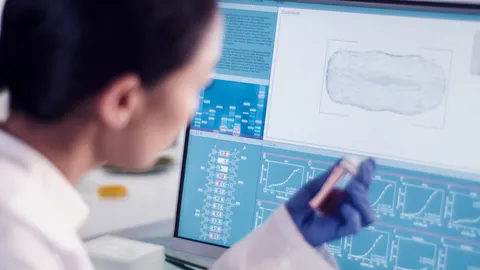 Scientist analyzing DNA and cellular data on a computer screen using advanced 4D imaging software.